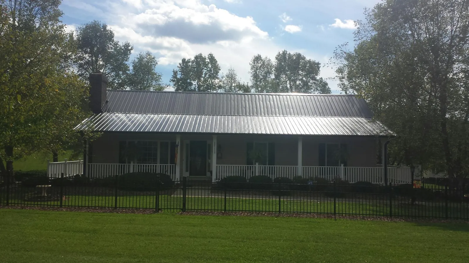 Gray metal roof on a brick ranch with a full width front porch — Gutter Guard Installation work by our crew in Union Springs