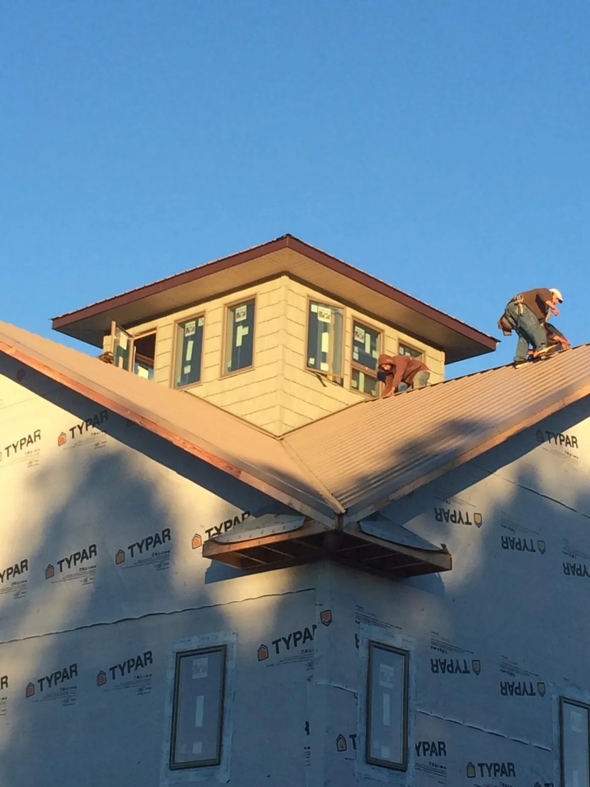 Roofers working around a rooftop cupola on a new metal roof at sunset — Roof Waterproofing in Union Springs by Roofing Brothers